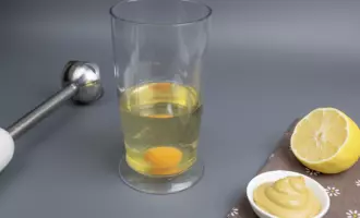 Налить растительное масло в стакан и разбить куриное яйцо.