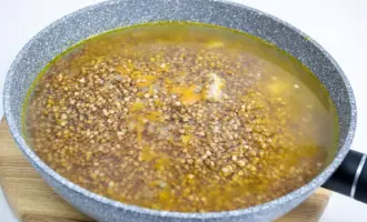 К обжаренным овощам с куриной грудкой добавить гречку и залить водой.